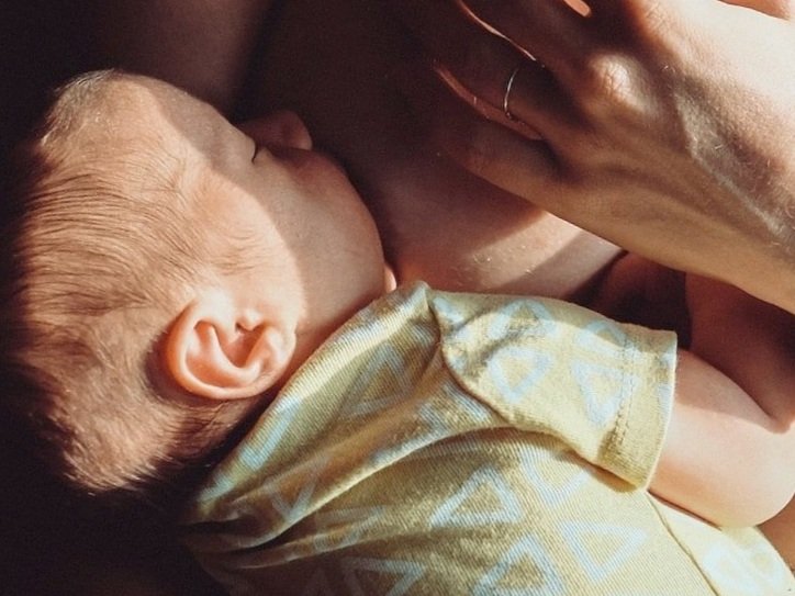 infant feeding at the breast with eyes closed and asleep